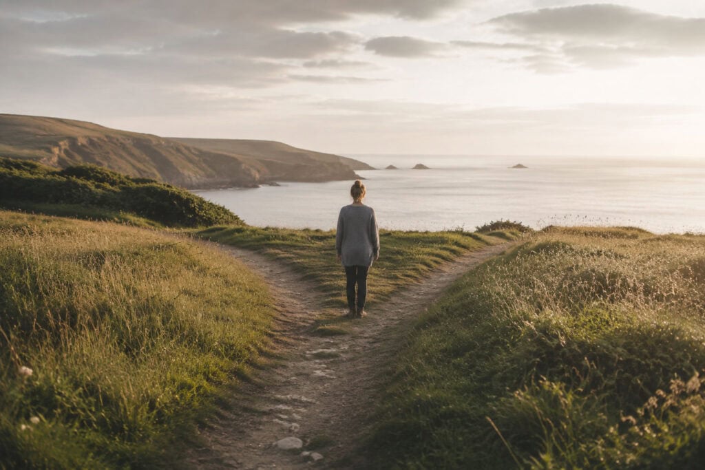 Woman pausing where a coastal path divides into two directions.